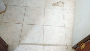 A bathroom with a toilet, a shower drain, and tiled walls. - Eldama Lodge (Gilgil)