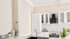 Een moderne keuken met witte kasten, een marmeren aanrecht en een zwarte spoelbak.