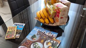 Een glazen eettafel met tijdschriften, een brood, bananen en cornflakes.