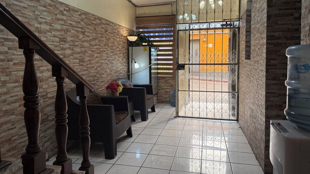 A hallway with a staircase, a water dispenser, and a seating area with a plant.
