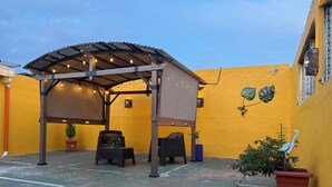 A covered patio area with seating and potted plants.
