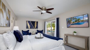 A hotel room with a bed, a ceiling fan, a painting of a pool, and a view of the outdoors. - Centrally located estate in Scottsdale with a heated pool, game room, and more! (Scottsdale)