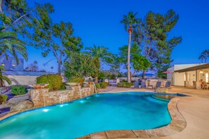 A swimming pool with a stone border, surrounded by palm trees and a patio area with outdoor furniture. - Centrally located estate in Scottsdale with a heated pool, game room, and more! (Scottsdale)
