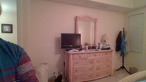 Una habitación con un aparador, un televisor y un espejo.