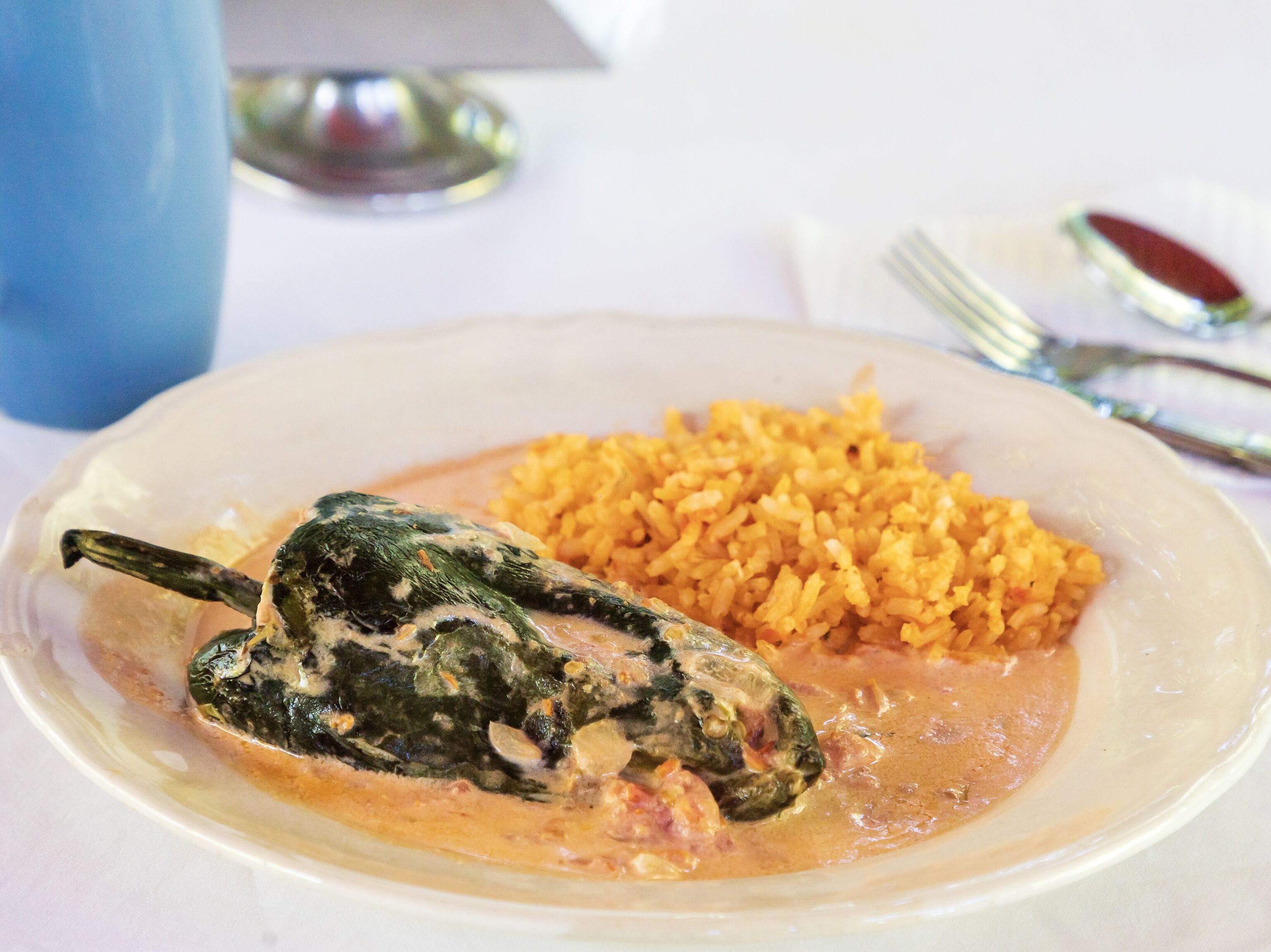 Un plato con un pimiento relleno, arroz y salsa.
