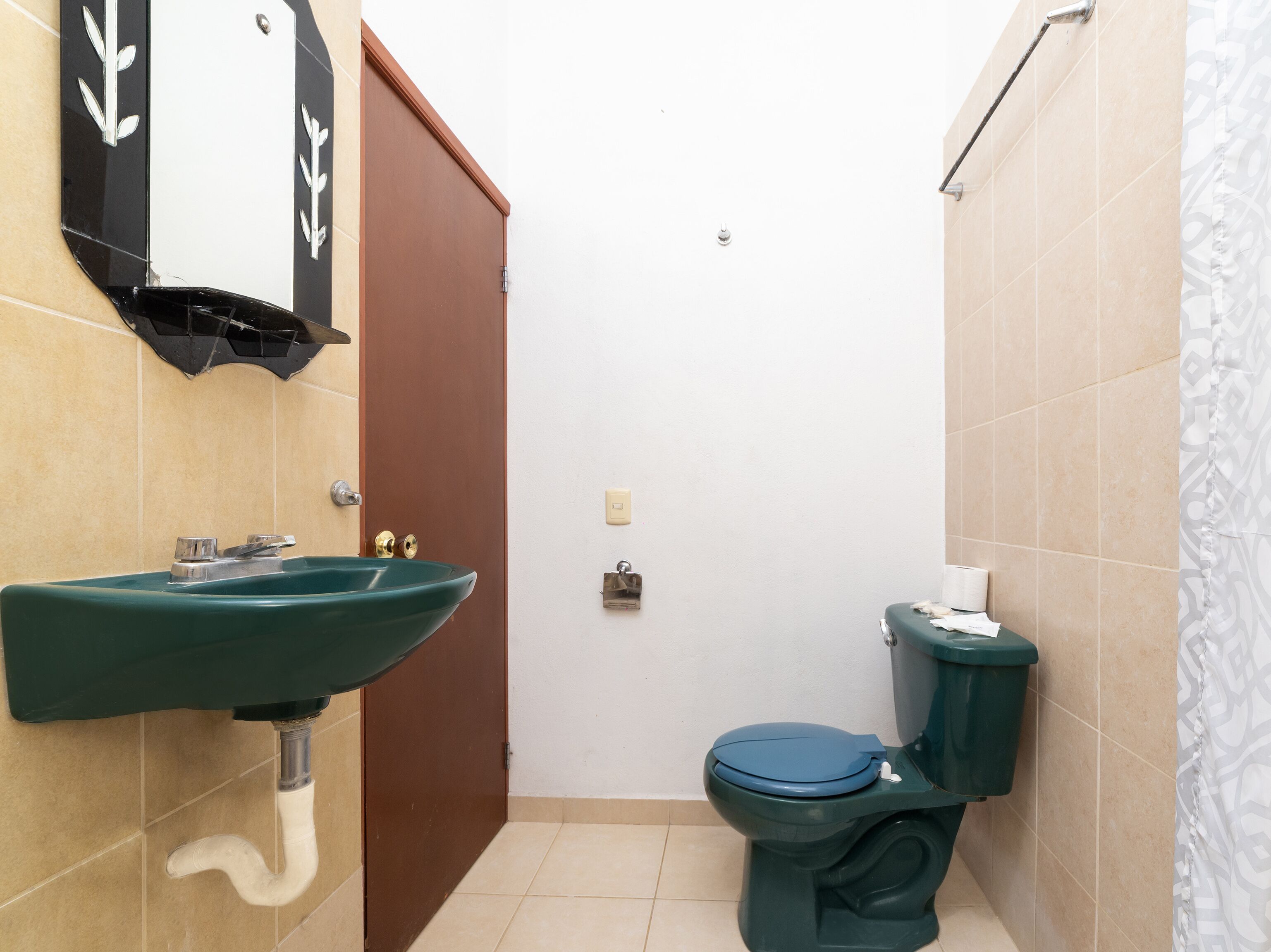 A small bathroom with a green sink, a toilet, and a door.