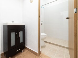 Un baño con un mueble negro, un inodoro y una zona de ducha.