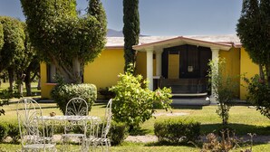 A yellow building with a porch, surrounded by well-maintained lawns and trees. - Villas el Paraíso, El Rollo (Tlaquiltenango)