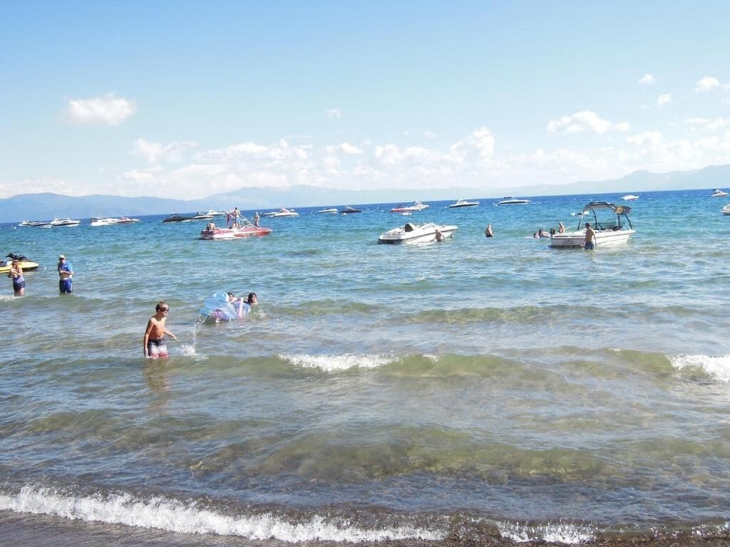 A beach with boats and people in the water.