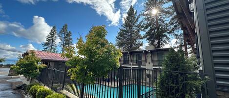 A residential area with a swimming pool, stone pathway, and a view of a house with a red roof.
