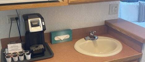 A compact kitchenette with a microwave, coffee maker, sink, and a dishwasher.