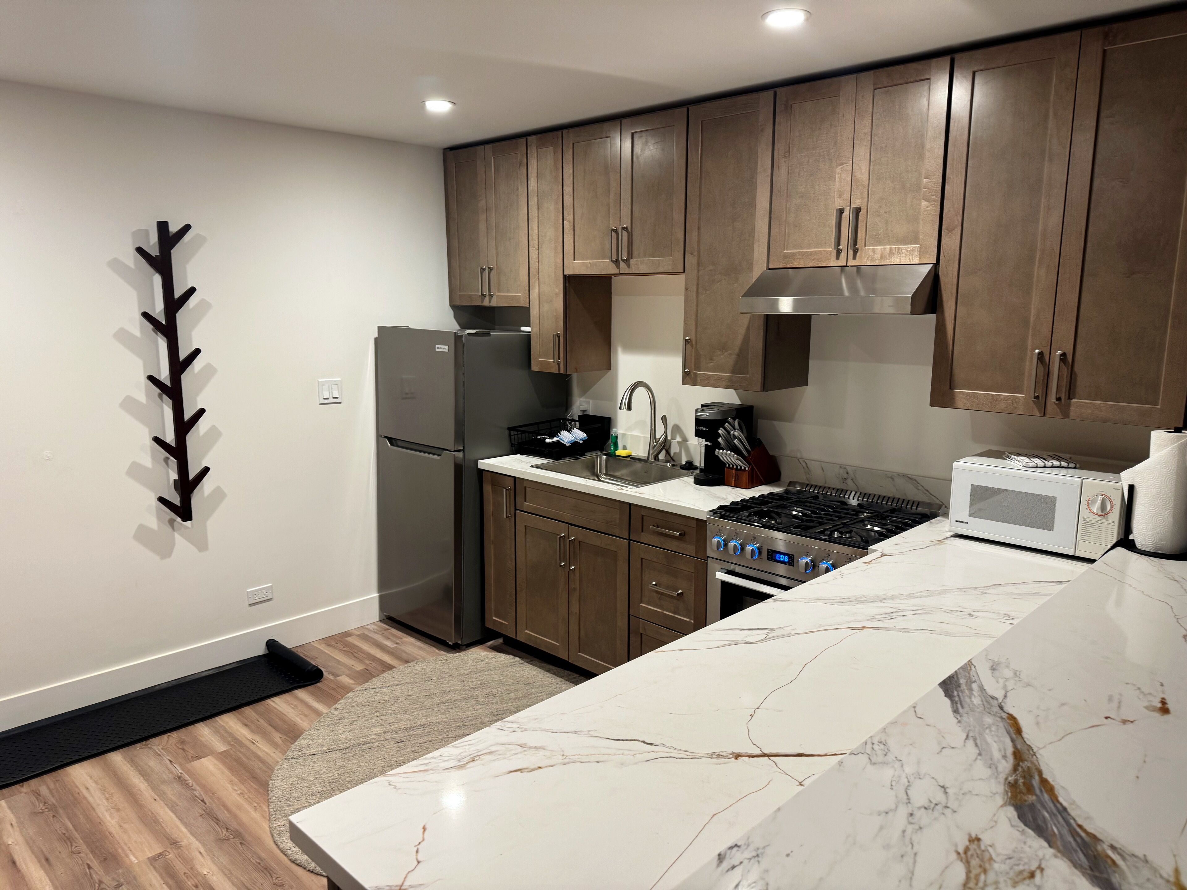 A modern kitchen with wooden cabinets, a stainless steel refrigerator, a gas stove, and a microwave.