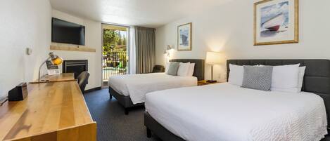 A hotel room with two beds, a desk, a flat-screen TV, and a painting of a sailboat.