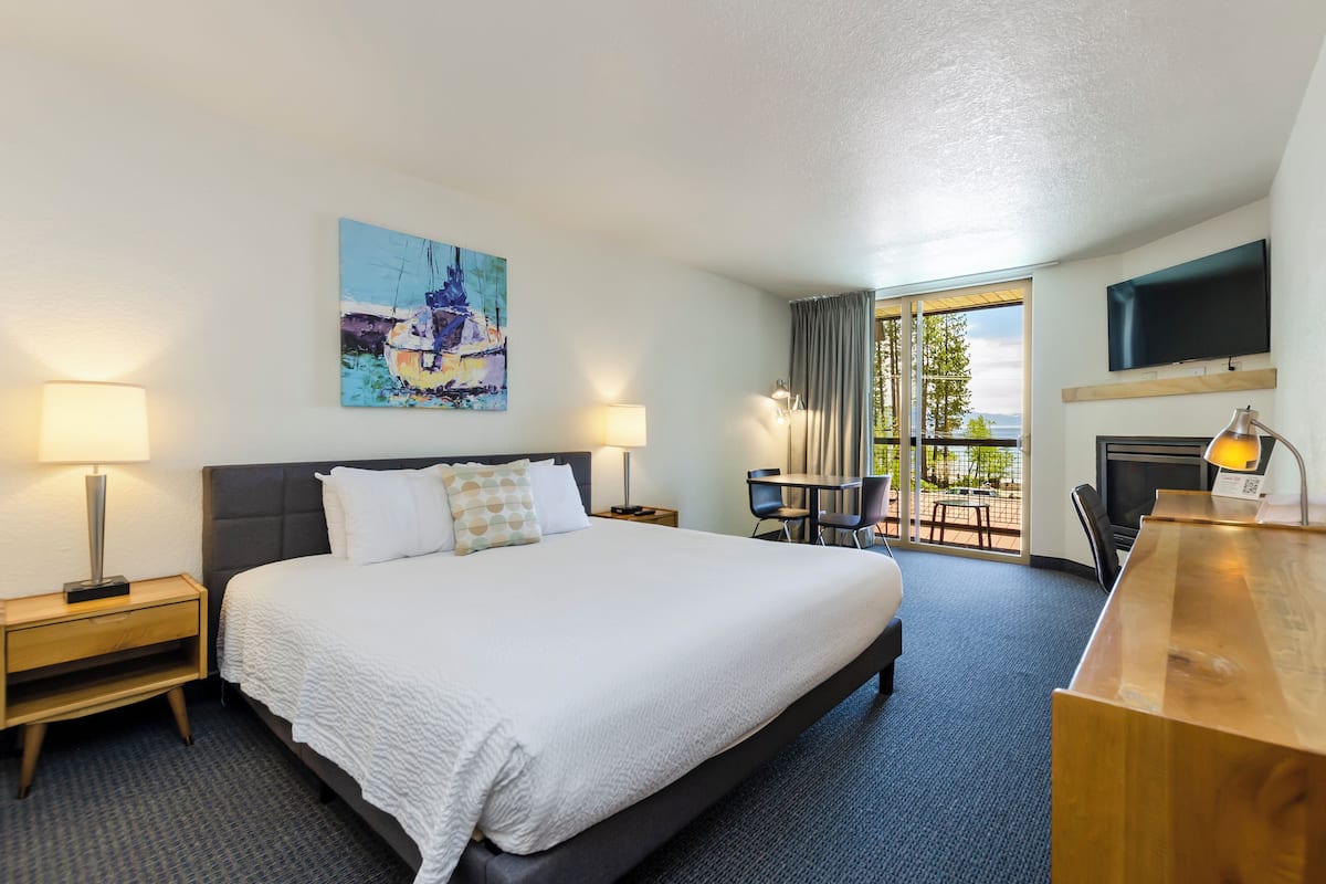 Une chambre d’hôtel avec un grand lit, un bureau, une chaise, une télévision et un tableau au mur.