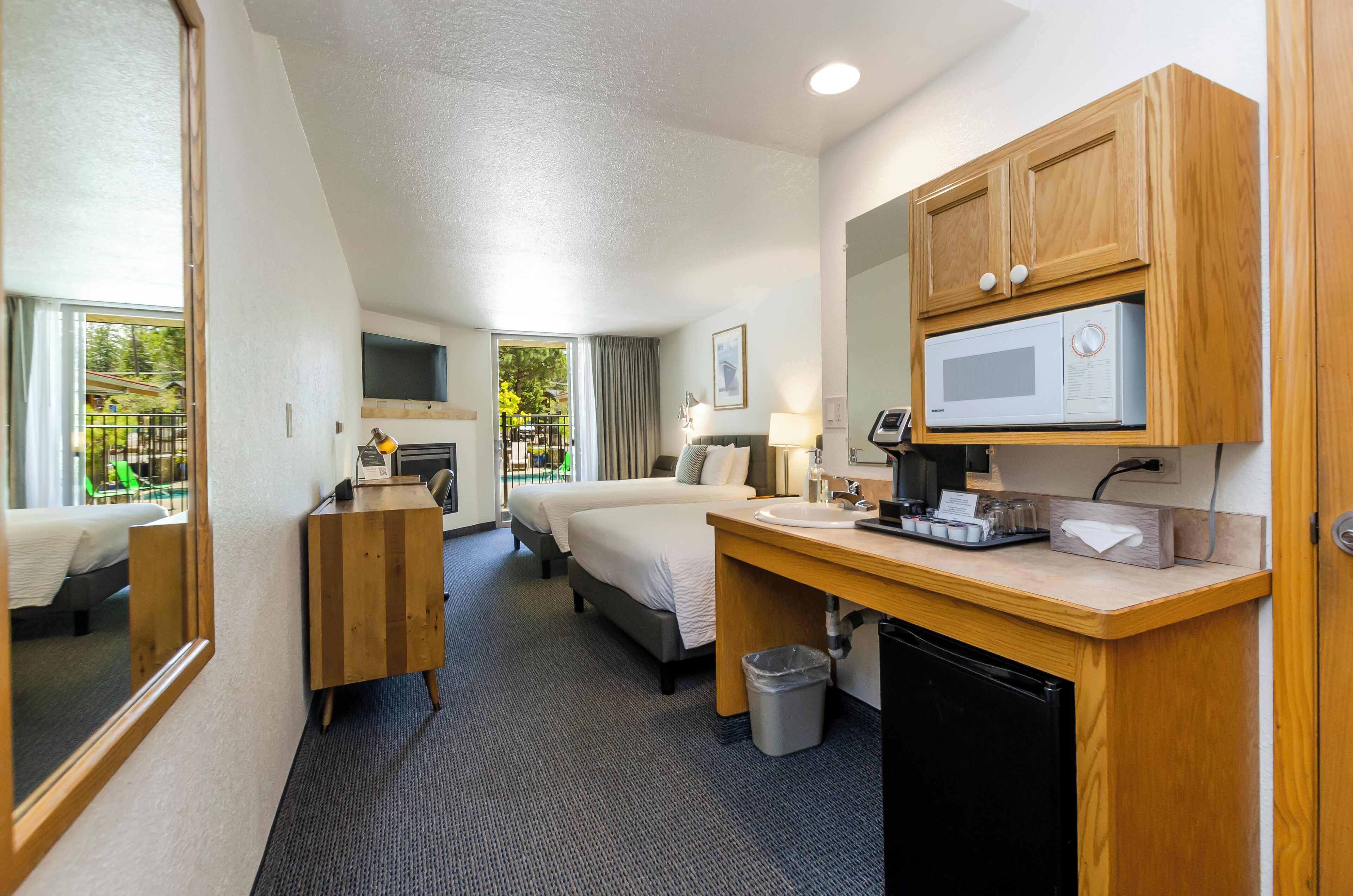 Une chambre d’hôtel équipée d’un lit, d’un bureau avec un micro-ondes, d’une poubelle et d’une fenêtre donnant sur un espace verdoyant.