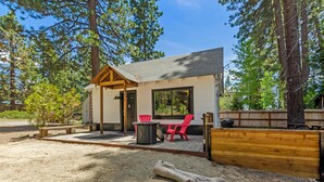 A cabin with a covered patio, a red chair, and a table. - Firelite Lodge (Kings Beach)
