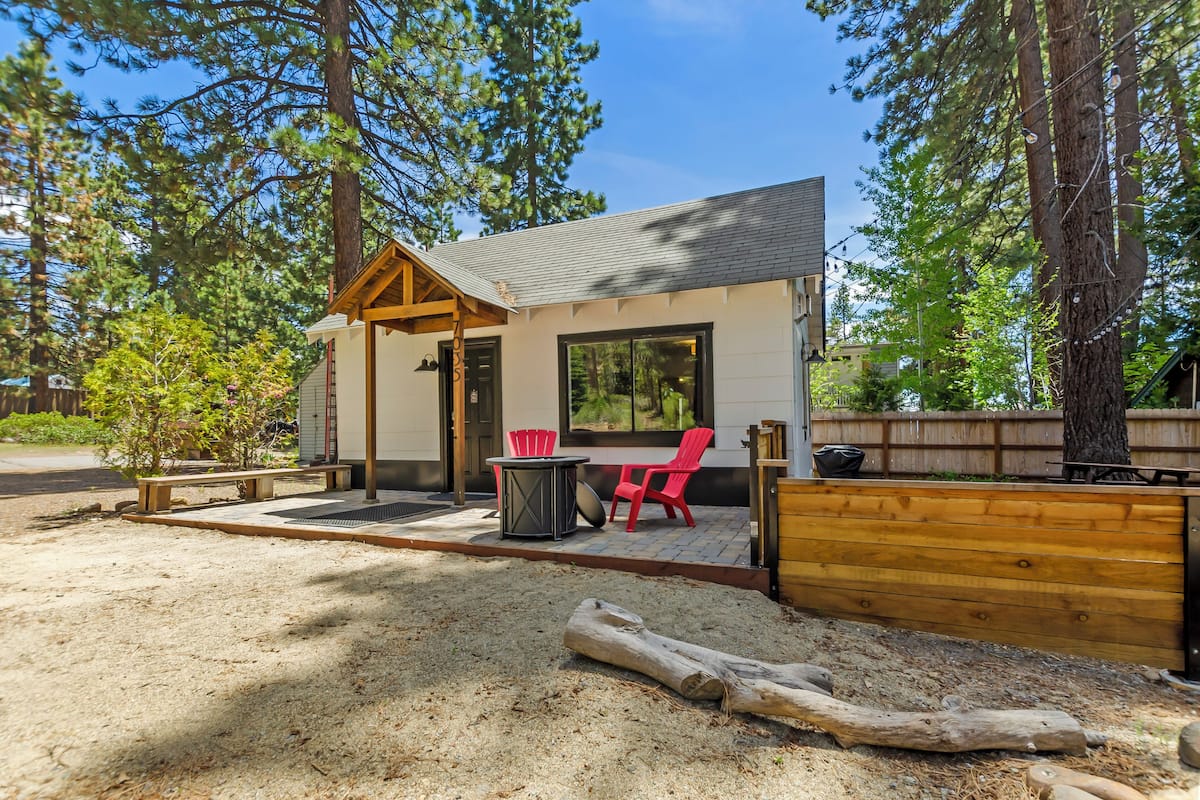 Une cabane dotée d’un patio couvert, d’une chaise rouge et d’une table.