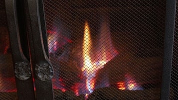 Ein Detailaufnahme eines Metallgitters, hinter dem ein Feuer brennt.