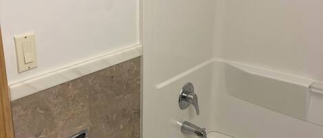 Un baño moderno con una bañera, un sujetapapeles y una toalla colgada en la pared.