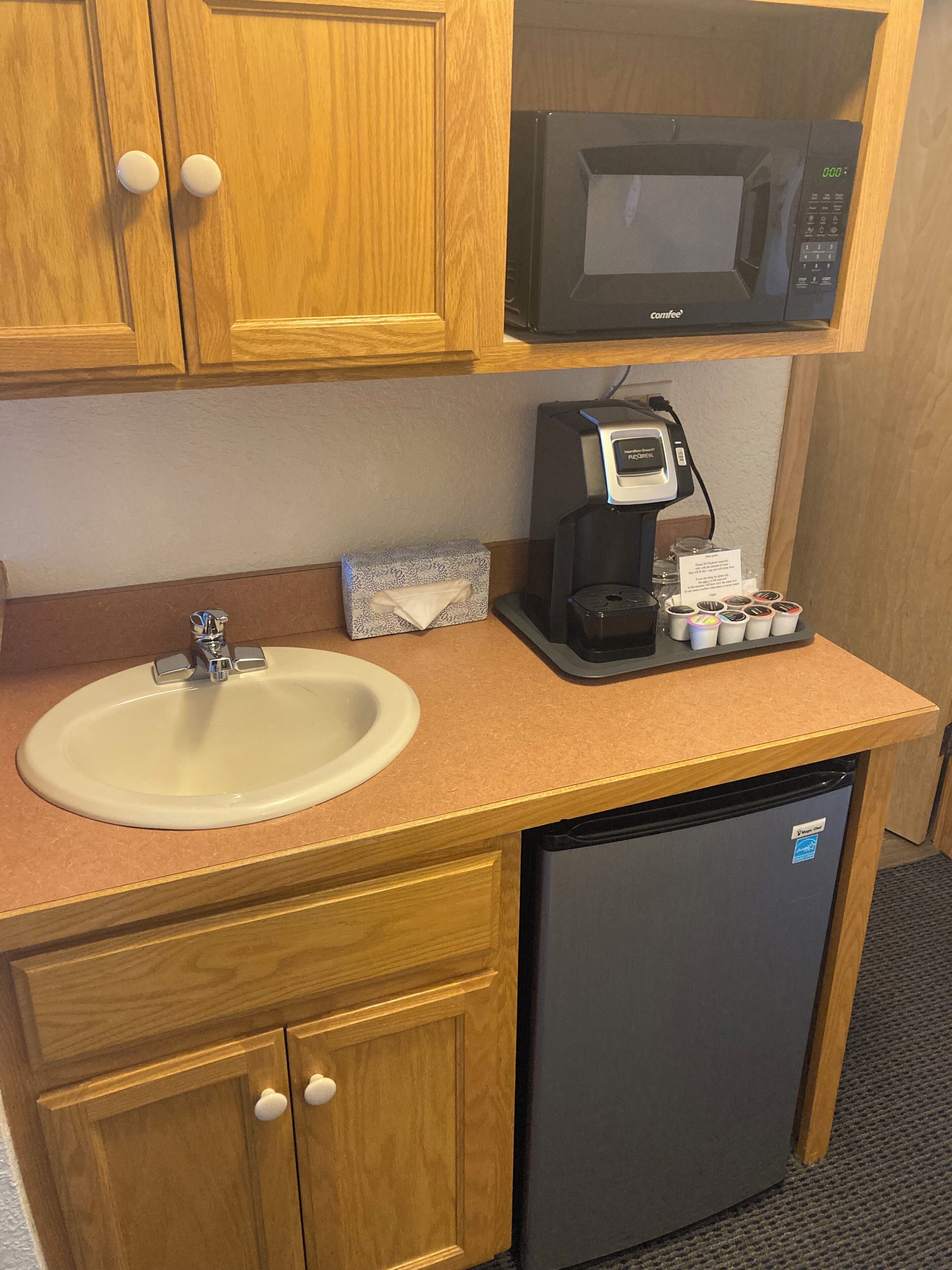 A compact kitchenette with a sink, a coffee maker, a microwave, and a refrigerator.