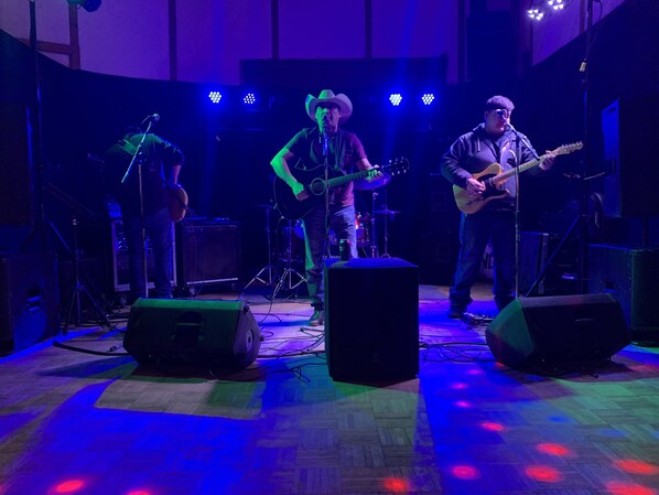 A band performing on a stage with musical instruments and speakers. - Sheridan Lawrence Inn (Fort Vermilion)