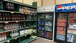 En butiksinredning med hyllor fyllda med olika sorters alkoholhaltiga drycker, inklusive flaskor med sprit och burkar med öl.