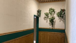 En hall med träpanel på väggarna och en grön accentvägg, som leder fram till en dörr.