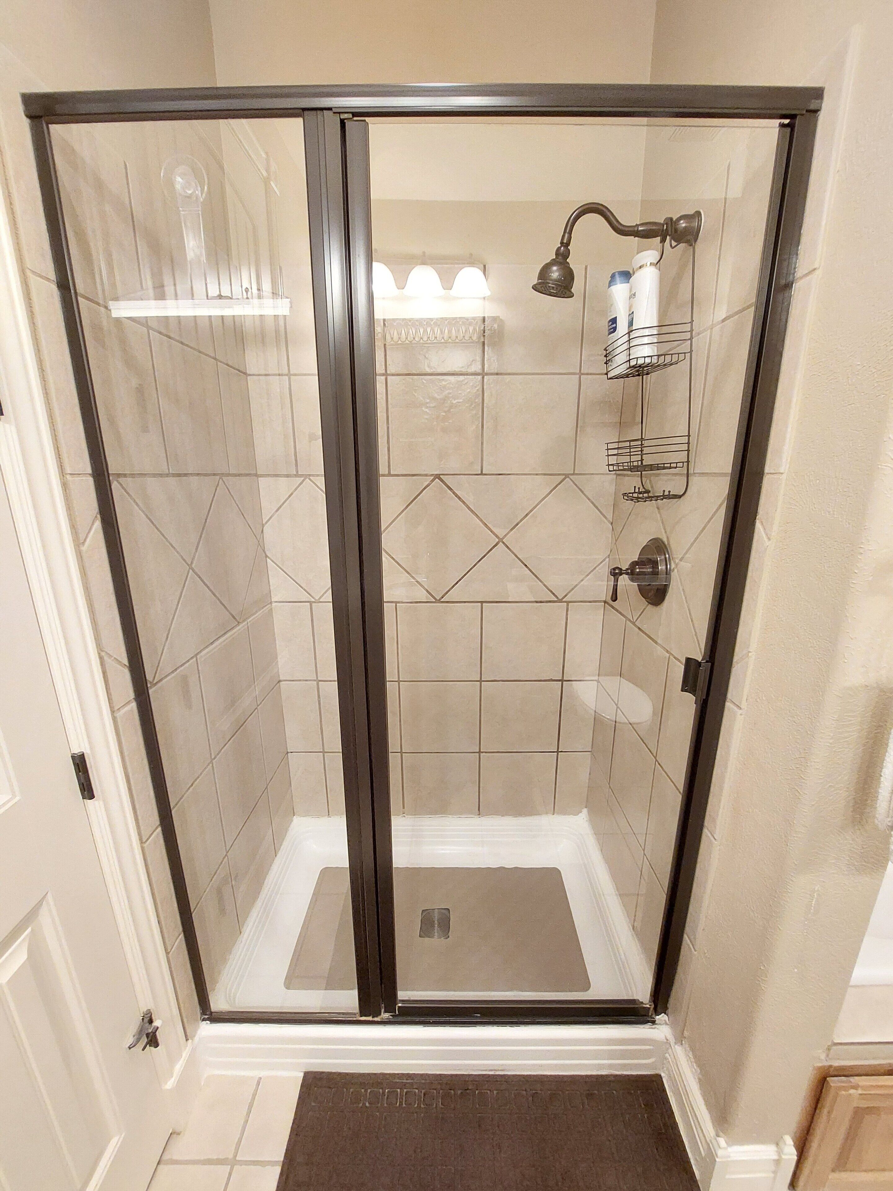 A walk-in shower with a glass door, tiled walls, and a showerhead.