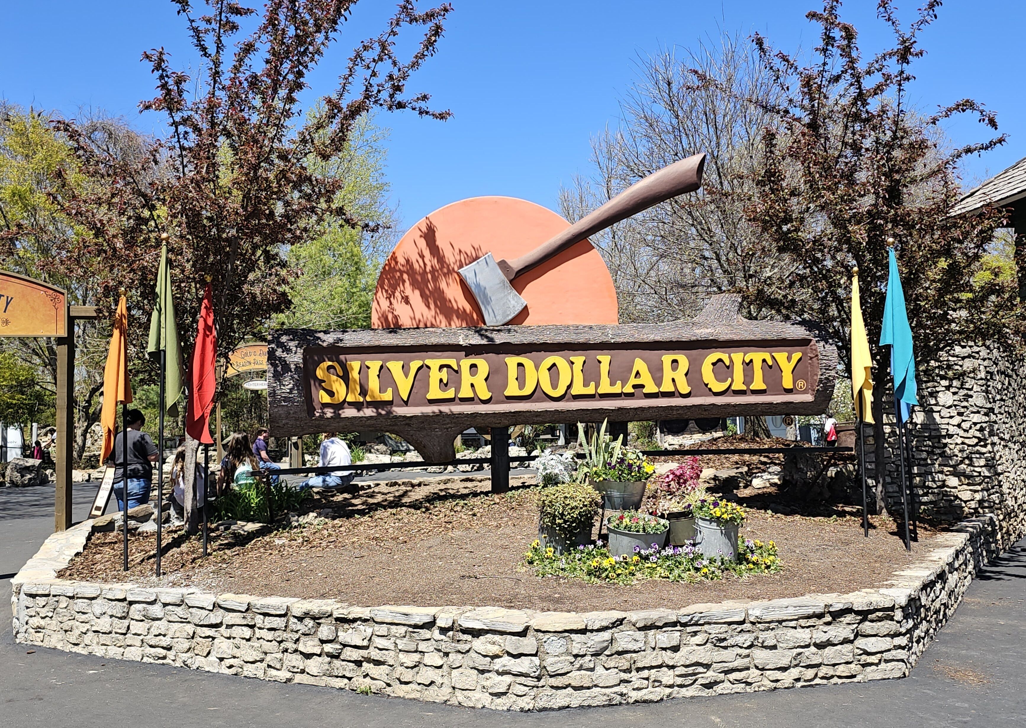 Une enseigne pour Silver Dollar City, avec une grande hache et un décor d’arbres en arrière-plan.