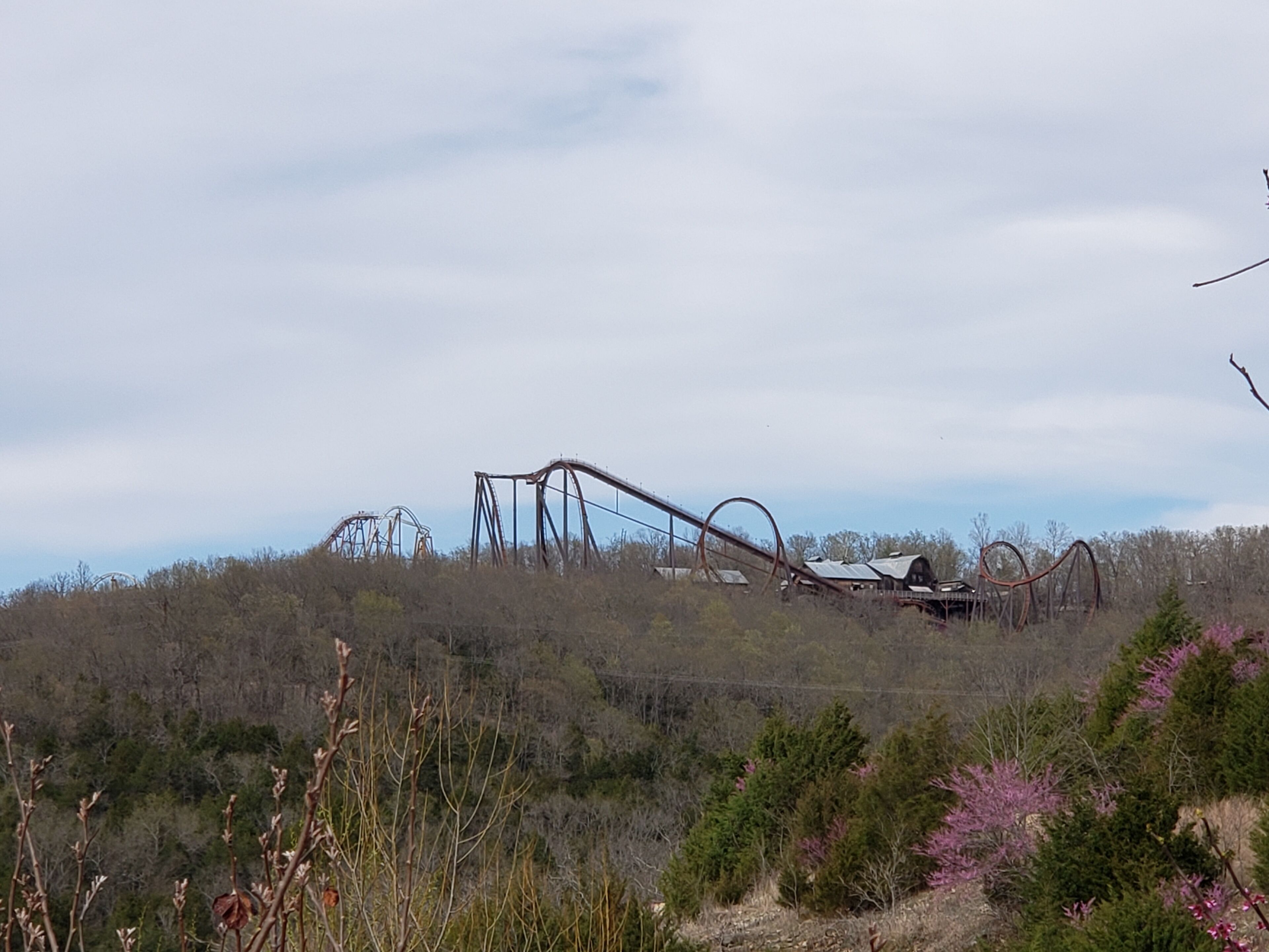 Un paysage rural avec une grande structure de montagnes russes rouillée.