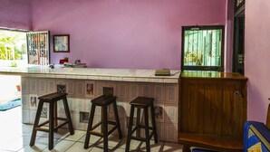 A bar area with stools, a counter, and a wooden cabinet. - Hotel Posada Agua Escondida (Cihuatlan)