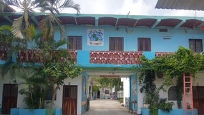 A building with a blue facade, a sign reading "Salida de Emergencia," and a dog lying on the ground. - Hotel Posada Agua Escondida (Cihuatlan)