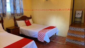 Habitación de hotel con dos camas, una mesita de noche, una lámpara fijada a la pared y una escalera con azulejos estampados.