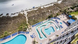 An aerial view of a resort with multiple swimming pools, sun loungers, and a beach area.