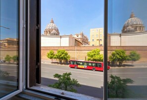 Ein roter Bus auf einer Stadtstraße, im Hintergrund große Kuppelgebäude.