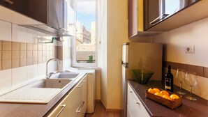 A kitchen with a window, a sink, a countertop with a basket of oranges, a bottle of wine, and two glasses. - Luxury Designer Rome  — St. Peter Dome View (Roma)