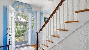A staircase with white balusters and wooden handrails, leading to a door with a blue frame and a glass window above it. - Lovely Shelter Island cottage with panoramic bay views, secluded, screened... (Shelter Island)