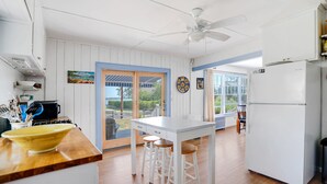 A kitchen with a wooden countertop, white cabinets, a ceiling fan, and a view of the outdoors. - Lovely Shelter Island cottage with panoramic bay views, secluded, screened... (Shelter Island)