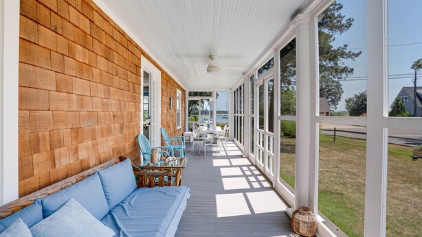 A covered porch with a wooden deck, white railing, and a view of the outdoors. - Lovely Shelter Island cottage with panoramic bay views, secluded, screened... (Shelter Island)
