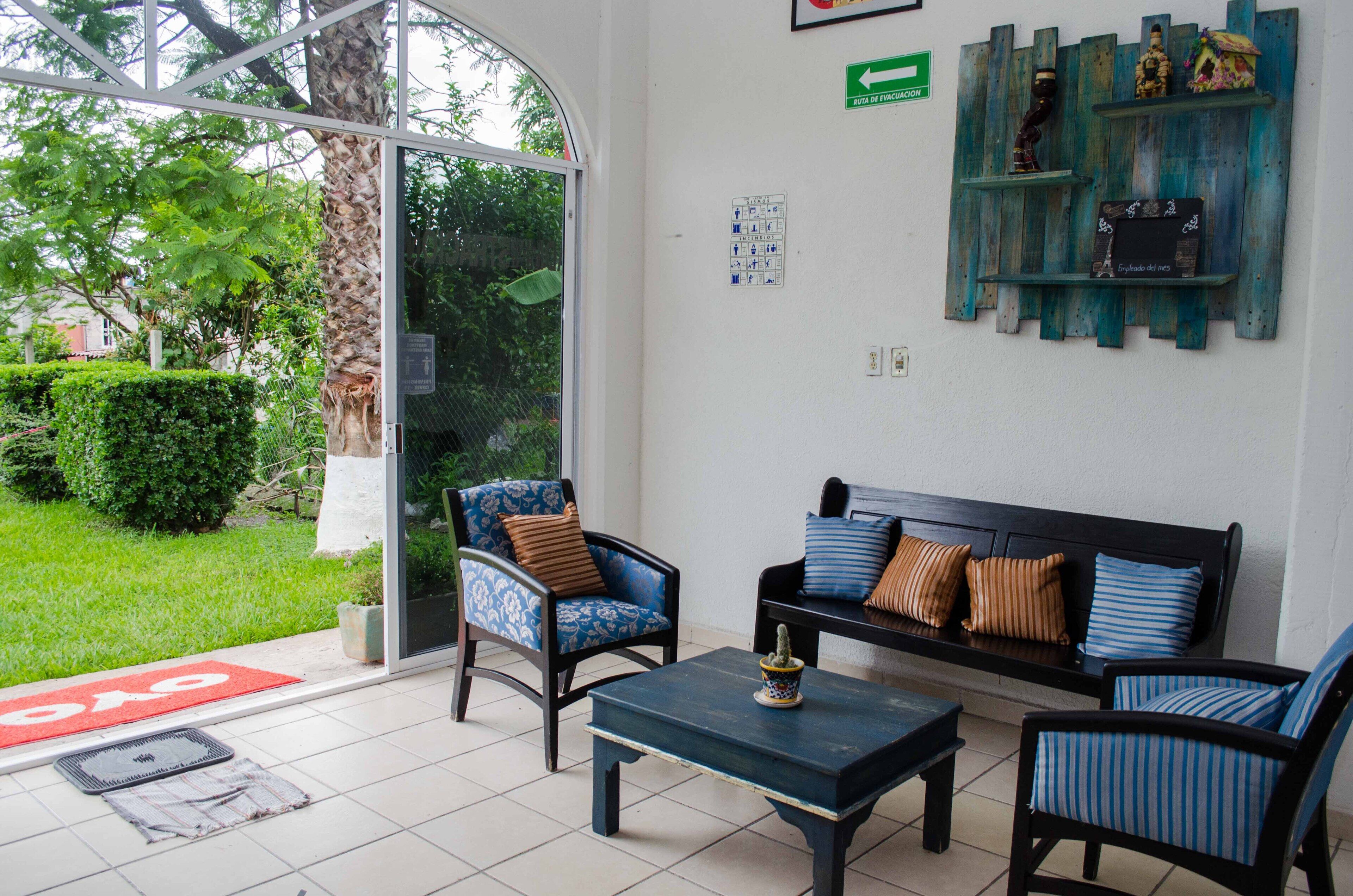 Un área de recepción con un sofá, sillas, una mesa de centro y una pared decorativa.
