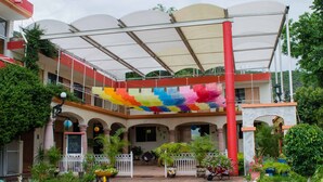 Une cour agrémentée d’une fresque colorée, d’une allée couverte et de plantes en pot.
