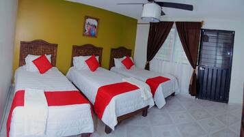 A hotel room with two single beds, a ceiling fan, a painting on the wall, and a window with curtains.