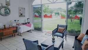 Une pièce comprenant une table à manger, des chaises, un canapé, un coin café et une grande porte-fenêtre coulissante donnant sur un espace extérieur.
