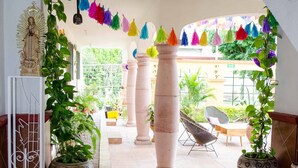 Un espace intérieur spacieux, agrémenté d’un banc vert, de plantes en pot et d’un escalier menant à un niveau supérieur.