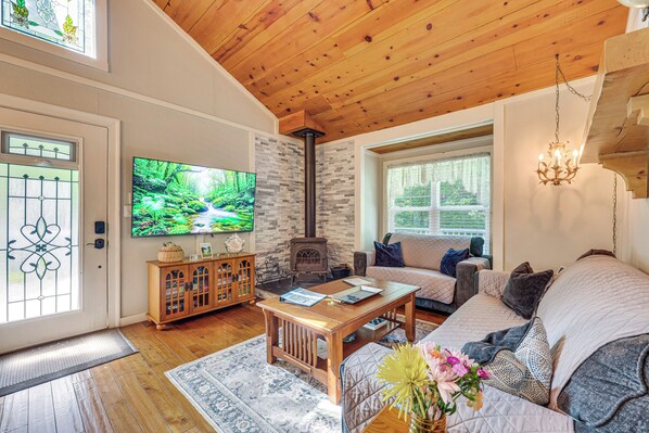 A cozy living room with a fireplace, wooden ceiling, and a comfortable sofa.