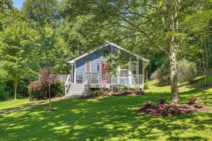 A house with a porch, surrounded by trees and a well-maintained lawn.