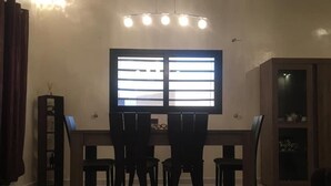 Ein Essbereich mit Holztisch, vier Stühlen, einer Vitrine und einem Fenster mit Jalousien.