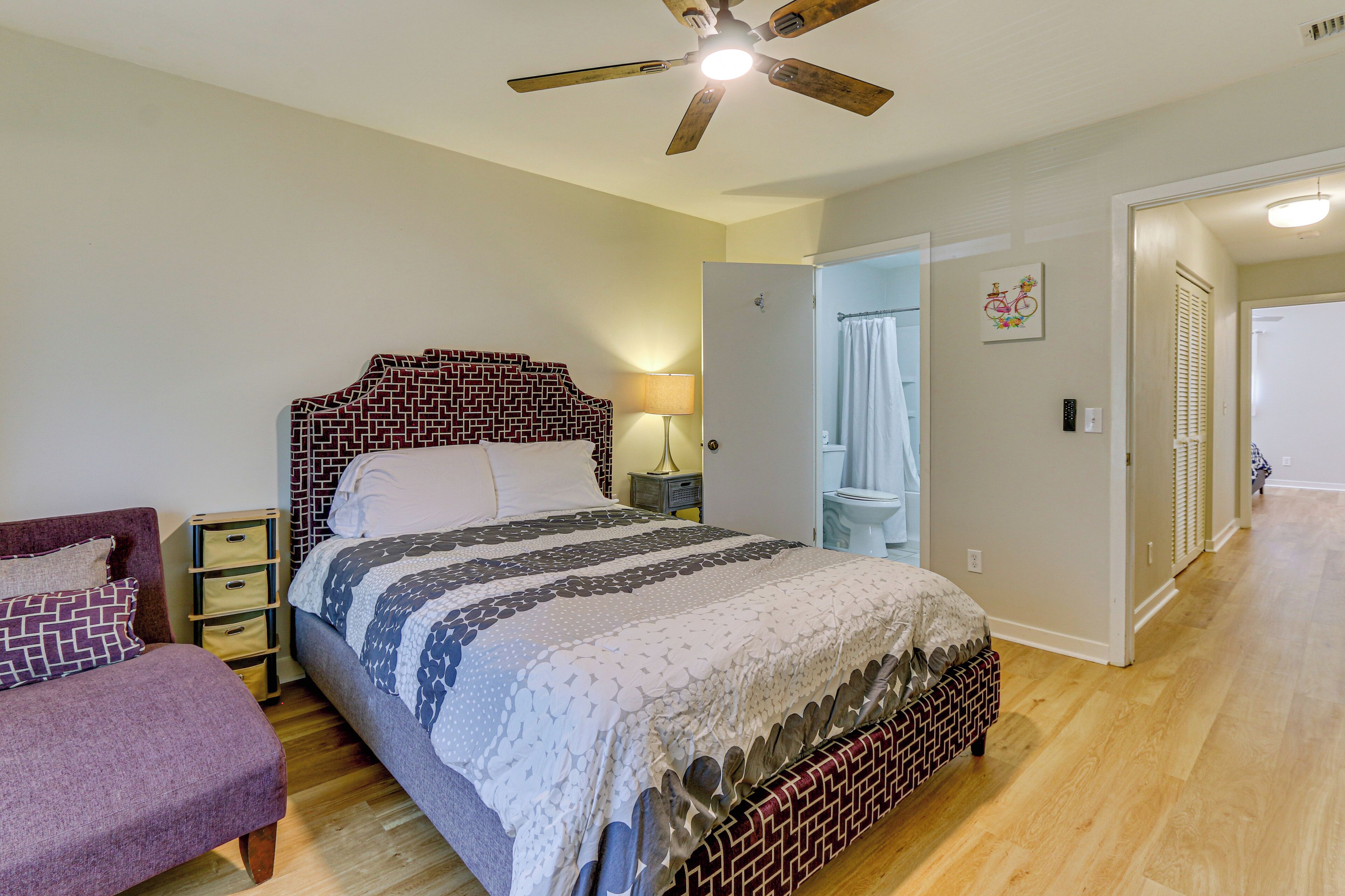 A bedroom with a bed, a nightstand, a lamp, a dresser, and a ceiling fan.