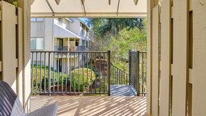 A covered outdoor area with a wooden bench, a metal gate, and a view of a building with multiple windows and a balcony. - Walk to Beach, Coligny Plaza | Hilton Head Villa (Hilton Head Island)