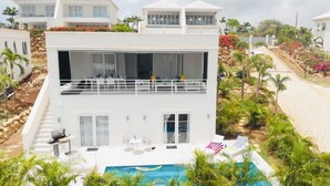 Une maison moderne à deux étages, dotée d’un balcon, d’une piscine et d’un jardin.